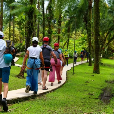 Group of tourists walking through tropical rainforest trail with canopy gear at Canopy Tour La Fortuna near Arenal Volcano.